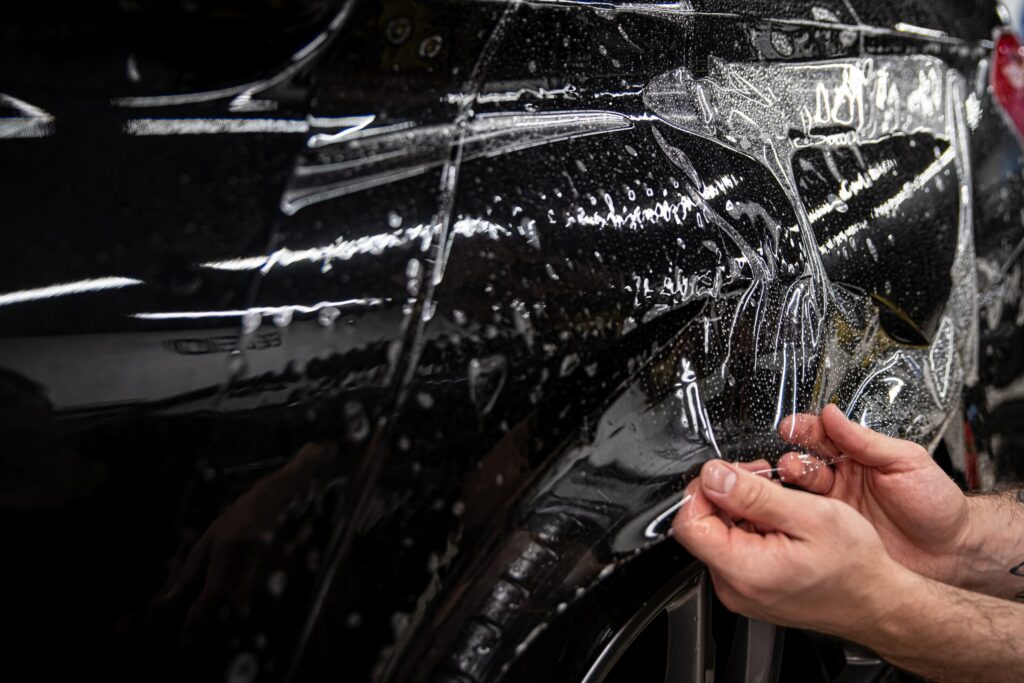 Car wrappping. Man car detailing studio worker appling transparent protection foil on car body. Services, Services, Pro Lettrage Drummond Inc.